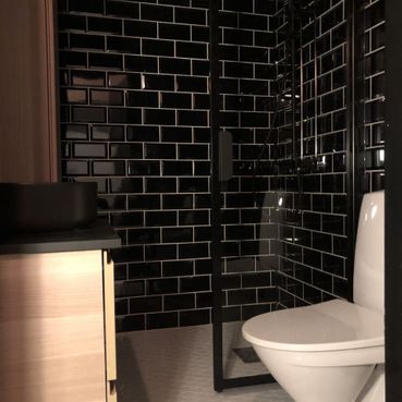 Mustalla laatoituksella sisustettu nykyaikainen kylpyhuone
