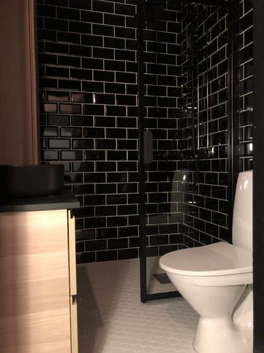 Mustalla laatoituksella sisustettu nykyaikainen kylpyhuone