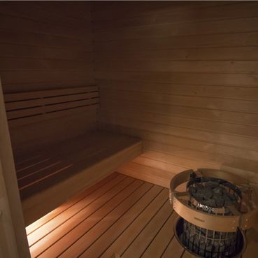 Minimalistinen vaalea sauna lattiaan upotetulla kiukaalla
