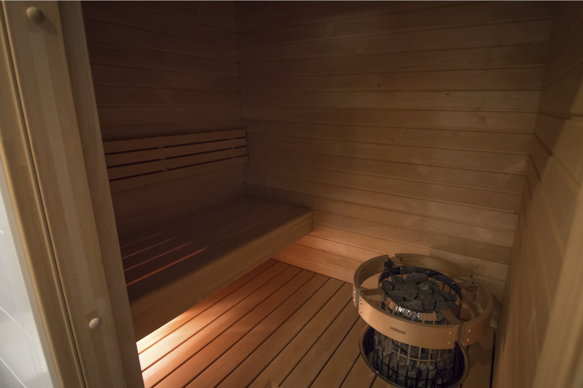 Minimalistinen vaalea sauna lattiaan upotetulla kiukaalla